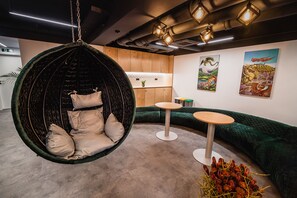 A modern interior with a hanging chair, green sofa, and small tables.