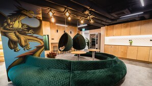 Ein modernes Interieur mit einem grünen, gepolsterten Sofa, hängenden Eiersesseln und einer Drachenmalerei.