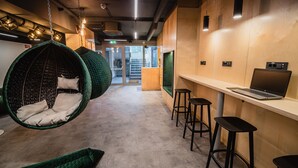 Ein modernes Interieur mit hängenden grünen Sesseln, einer Bar mit Hockern und einem Laptop auf einer Theke.
