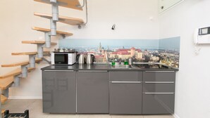Una cocina moderna con vista a la ciudad, microondas integrado y hervidor de acero inoxidable.