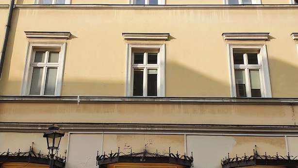 Un edificio de varios pisos con fachada amarilla, múltiples ventanas y una entrada principal a nivel de calle con puerta.