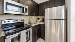 A modern kitchen with stainless steel appliances, dark cabinetry, and a tiled backsplash. - URBAN4-1 | relax after exploring Brickell City (Miami)