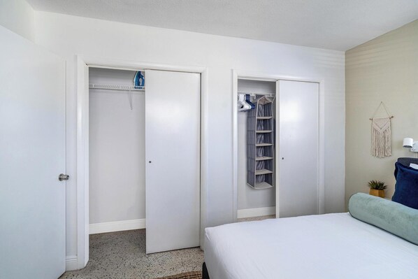 Ein Schlafzimmer mit einem Bett, einem Schrank mit Regalen und einer Wandlampe.