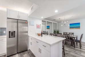A modern kitchen with white cabinetry, stainless steel appliances, and a central island. - JupRent's Ocean Walk Paradise - Close to all- 6 min walk to beach - 3Bed/3Bath - (Jupiter)