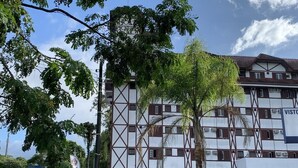 A multi-story building with a white facade and brown accents, featuring a symmetrical window pattern and a visible 'VISTAS' sign. - Partner Hotéis by Holz (Joinville)