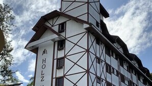 A hotel with a distinctive architectural style, featuring a prominent tower and a sign reading "HOLZ HOTEL". - Partner Hotéis by Holz (Joinville)