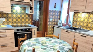 Una cocina con armarios de madera, estufa, pileta y una mesa de comedor con sillas.