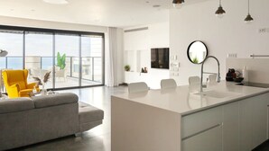 Een moderne keuken met een centraal eiland, een zithoek met stoelen en een groot raam met uitzicht.