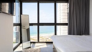 Een slaapkamer met een groot raam, een bed en een spiegel.