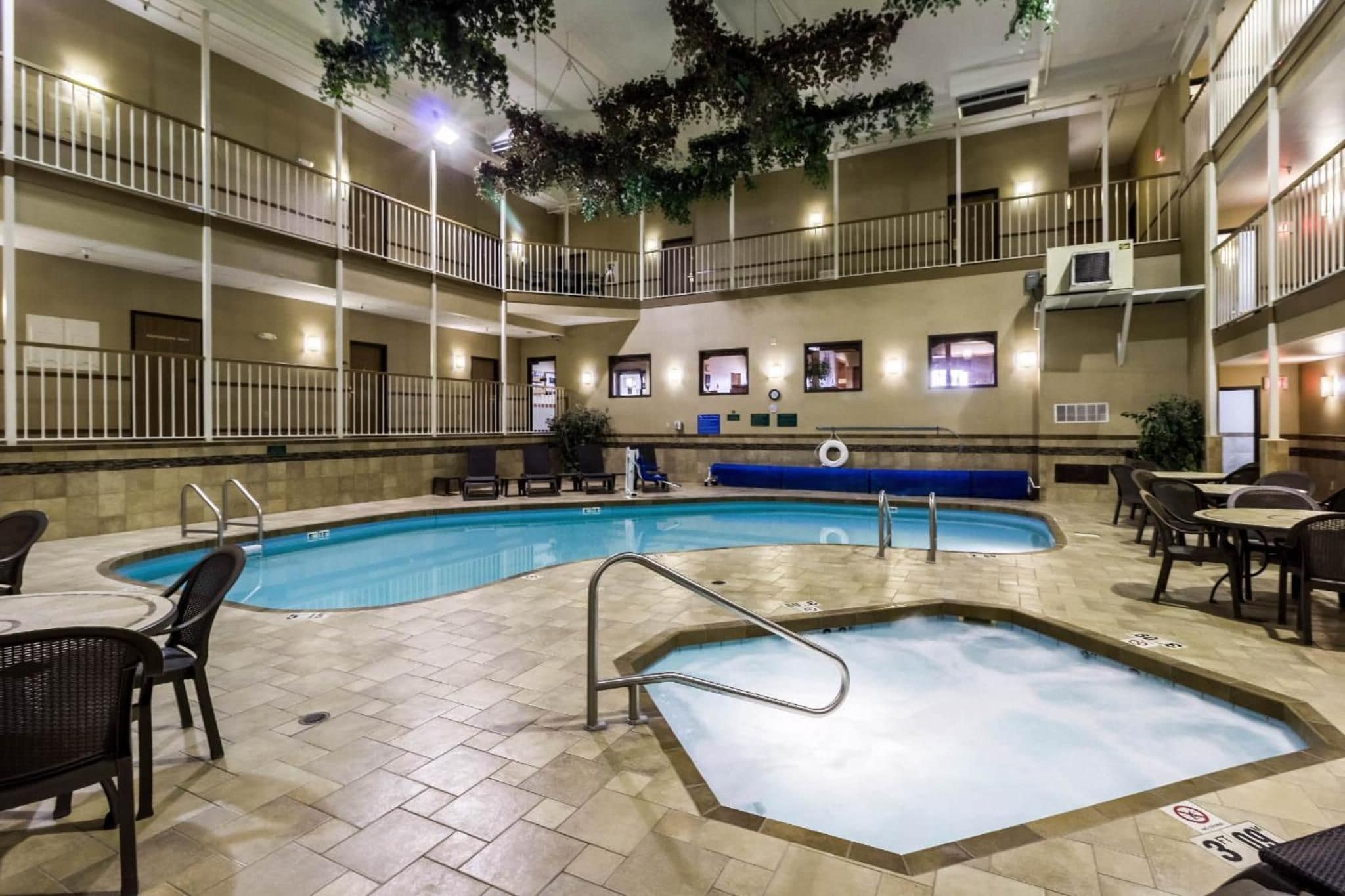 Una piscina interior con varios niveles de balcones, sillas de descanso y mesas.