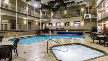 Una piscina interior con varios niveles de balcones, sillas de descanso y mesas.