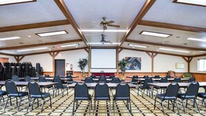 A conference room with multiple tables and chairs, a projector screen, and a ceiling fan. - Studio 6 Minot, ND (Minot)