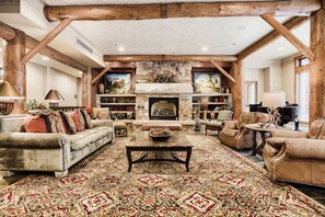 A spacious living room with a fireplace, leather sofas, a patterned rug, and wooden beams. - Oversized Luxury Ski in Ski out/Shared Pool and Hot Tub/Private Deck (Keystone)