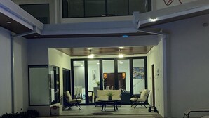 Una casa moderna con piscina, un patio cubierto y un comedor con mobiliario exterior.