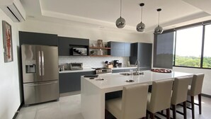 Una cocina moderna con una isla central, electrodomésticos de acero inoxidable y un ventanal con vistas al exterior.