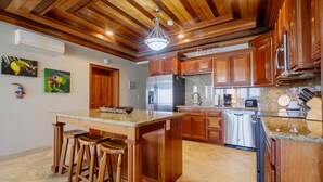 Una cucina con mobili in legno, un piano di lavoro in granito e un'isola centrale con sgabelli.