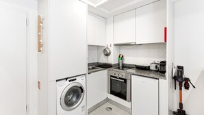 A compact kitchen with a washing machine, oven, and microwave. - GuestReady - Easygoing Pool to River (Vila Nova de Gaia)