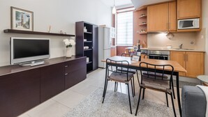 A modern kitchen with a dining area, wooden cabinets, a built-in microwave, and a flat-screen TV.