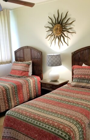Une chambre avec deux lits, une décoration murale en forme de soleil, une lampe et une table de chevet.