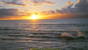 A sunset over the ocean with waves and clouds.
