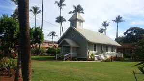 A church with a steeple, surrounded by a well-maintained lawn and palm trees.