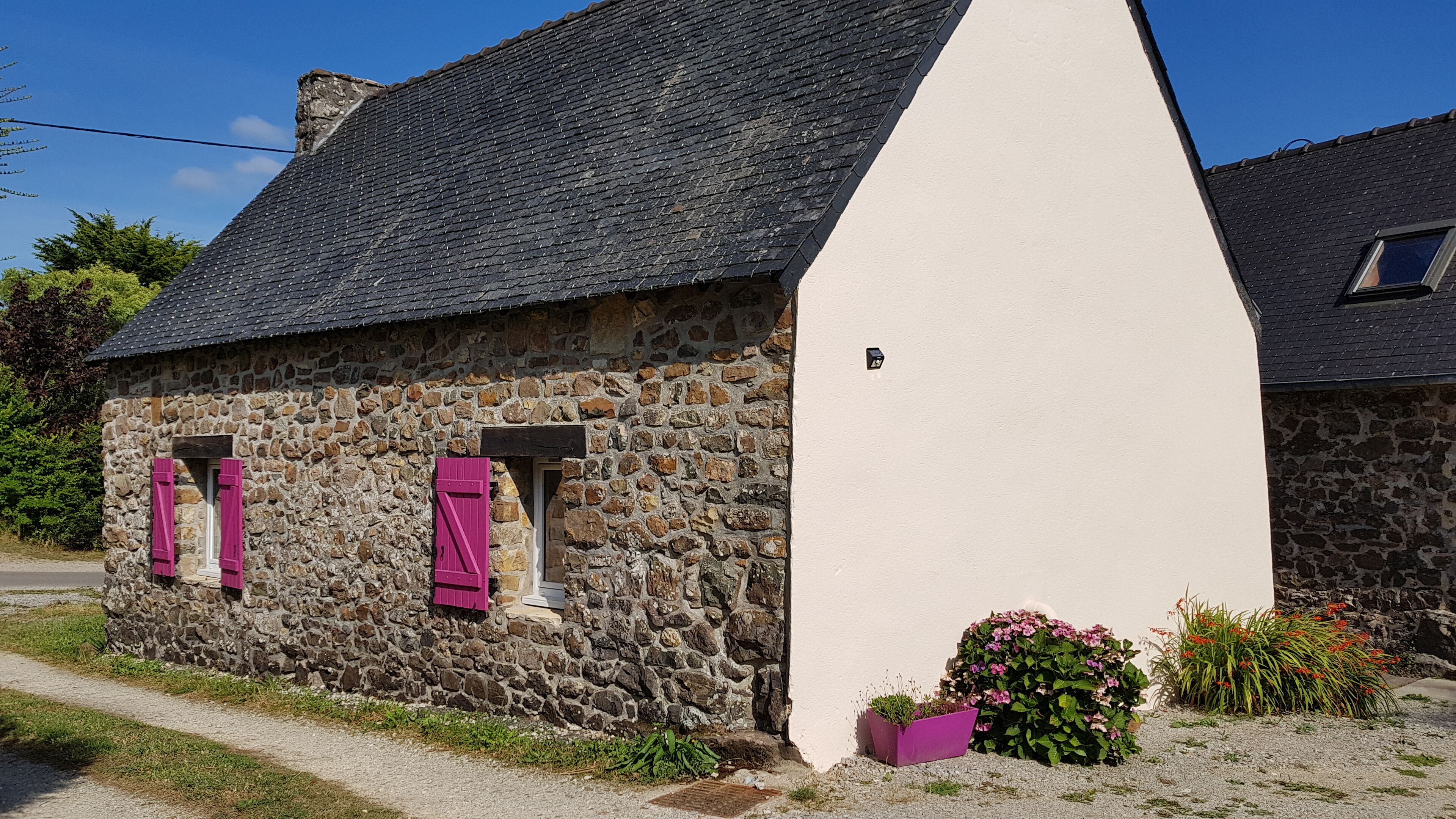 Une maison en pierre avec une façade blanche et un toit à forte pente.