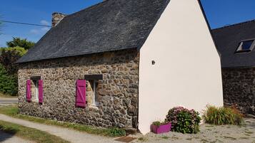 Una casa de piedra con fachada blanca y techo a dos aguas.