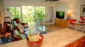 Una sala de estar con televisor, un comedor con mesa y sillas, y una cocina con mostrador.