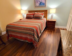 A neatly made bed with patterned bedding, two bedside lamps, a wooden nightstand, and a bench. - 1Bed Oceanview and Sunset Vw! Pool Spa (Lahaina)