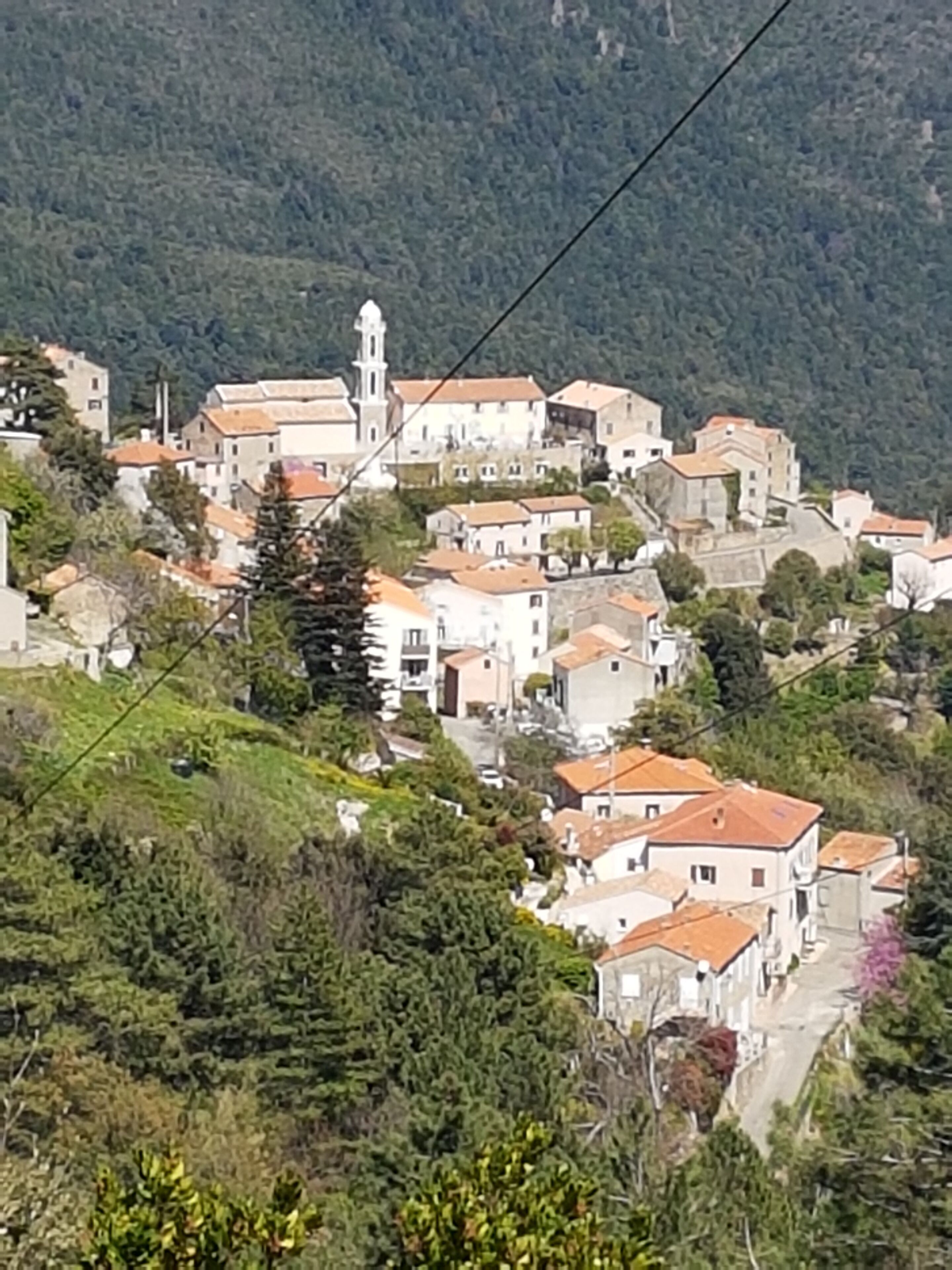 Un borgo collinare dall'architettura tradizionale, caratterizzato da una chiesa con un campanile ben visibile.