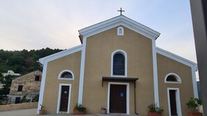 Une église dotée d’une entrée principale, flanquée de deux entrées latérales, et surmontée d’une croix.
