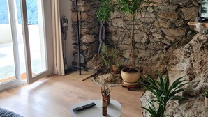 Un salon avec un mur en pierre, un canapé, une table basse et des plantes en pot.