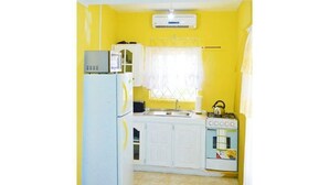 Una cucina compatta con frigorifero, forno a microonde, fornelli e lavello.
