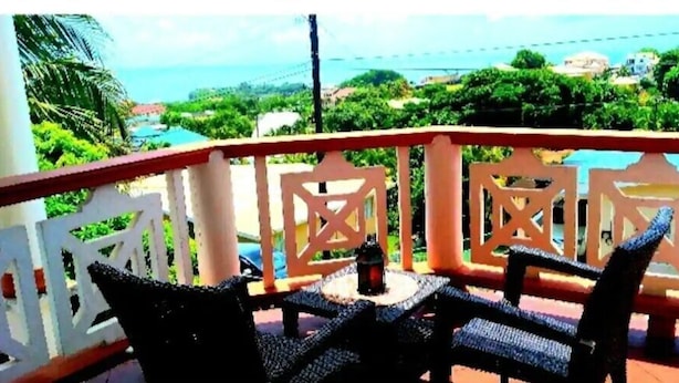 Un balcone con mobili in vimini e vista sull'oceano e sul verde.