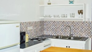 A kitchen with white cabinets, a tiled backsplash, a stove, a microwave, and a sink. - Samuels Apartment #2 (Kingstown)