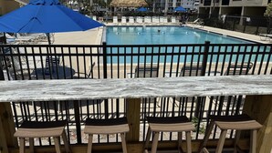 Un bar situé au bord de la piscine, avec des tabourets en bois et un comptoir en marbre.