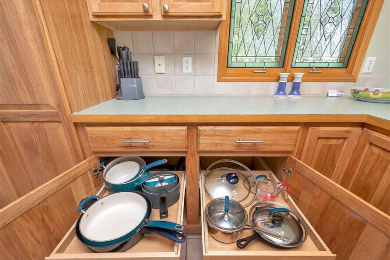 A kitchen with wooden cabinets, a countertop, and a window with green glass panes.