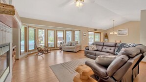 A spacious living room with a fireplace, a large sectional sofa, and a rocking chair. - Houghton Lake Getaway w/ Pontoon (Houghton Lake)
