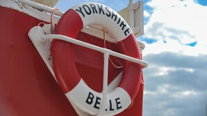 En redningskranse med teksten "Yorkshire" og "Belle" på en rød og hvid båd.