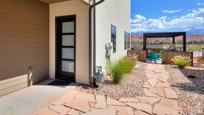 A modern house with a stone patio, outdoor seating, and a view of mountains. - Luxury twin home.  Beautiful views. Private hot tub. Covered outside patio.  (Moab)