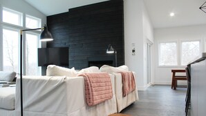 Een moderne woonkamer met een grote bank, een klein houten bankje en een open haard.
