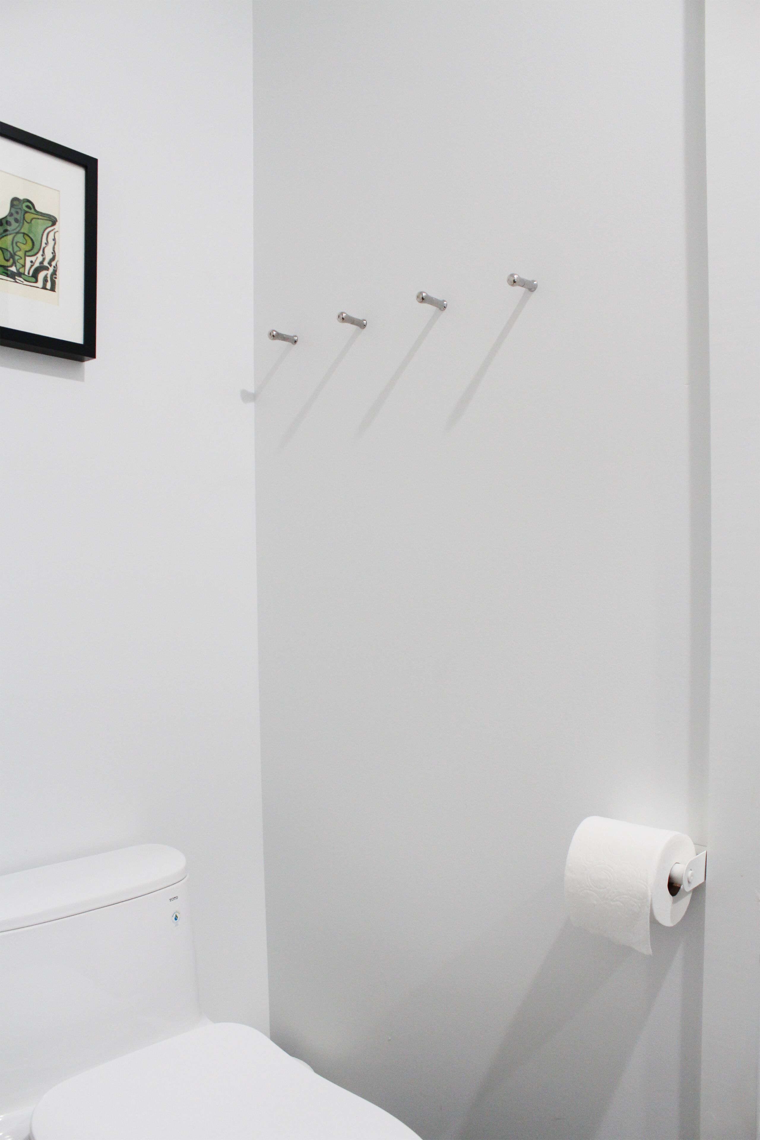 Une salle de bain moderne avec des toilettes, un tableau encadré au mur et un porte-rouleau de papier toilette.