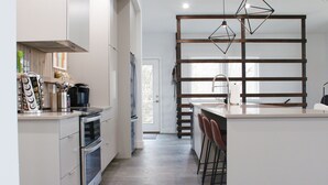 Een moderne keuken met roestvrijstalen apparatuur, een houten bar en hangende lampen.