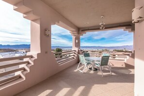 Ein Balkon mit Tisch und Stühlen, Blick auf Berge und einen klaren Himmel.