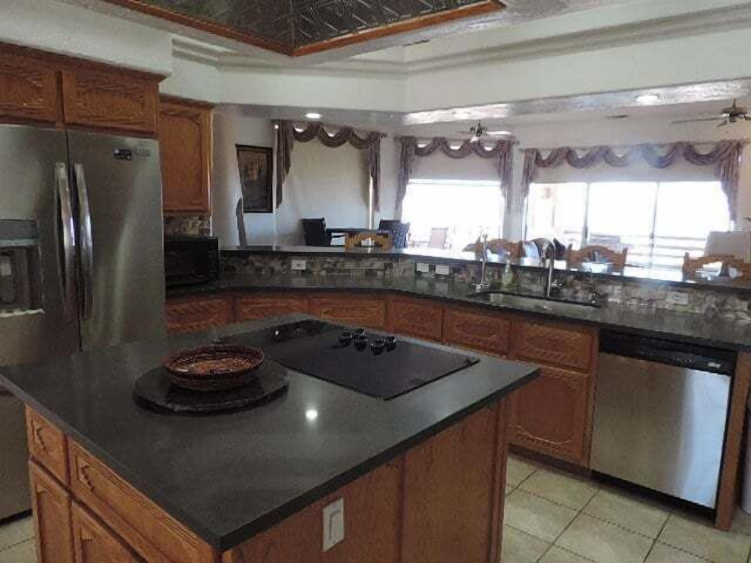 A kitchen with a large island, stainless steel appliances, and wooden cabinetry.