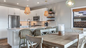 A modern kitchen with white cabinets, stainless steel appliances, and a central island with seating. - 3 Bedroom Private Home at Waikoloa Beach with Pool (Waikoloa)