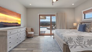 A bedroom with a large bed, a ceiling fan, a view of the outdoors, and a sliding glass door leading to a balcony. - 3 Bedroom Private Home at Waikoloa Beach with Pool (Waikoloa)