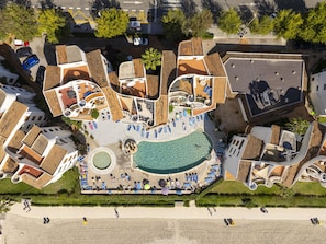 An aerial view of a resort with a central swimming pool, multiple lounge areas, and a beach. - Apartamento Carabela 51· 2 bedrooms · 3 beds · 1 bath (Puerto de Alcudia)