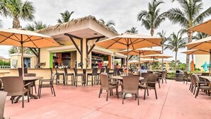 An outdoor patio area with tables and chairs, umbrellas, and a bar area. - Beautiful Hutchinson Island Condo - Steps to Ocean (Fort Pierce)