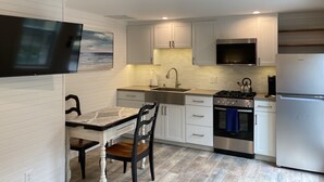 A modern kitchen with white cabinetry, a built-in oven, a stove, and a refrigerator. - Beach Walk Bungalow 1Bedroom 1Bath, 4 blocks to the beach!! Private Courtyard (St. Simons Island)